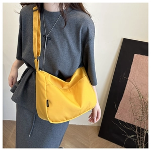 Detail of yellow nylon crossbody bag with adjustable strap and front pocket storage
