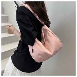 Pink nylon tote bag shown on shoulder featuring wide straps and minimalist slouchy design