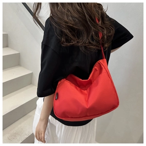 Detail of red canvas bucket bag with wide strap and minimalist branding on the side