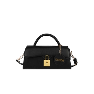 Détail d'un sac à bandoulière rectangulaire noir avec boucle dorée et breloque ronde