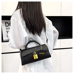 Detail view of black matte leather shoulder bag featuring a gold padlock and fashion tag