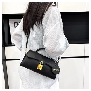Détail d'un sac bandoulière en cuir PU noir avec boucle dorée et pendentif de mode