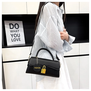 Close-up of black leather handbag with gold lock detail and fashion tag on model