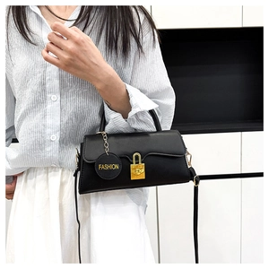 Detail of matte black leather bag with gold buckle lock and fashion letter pendant