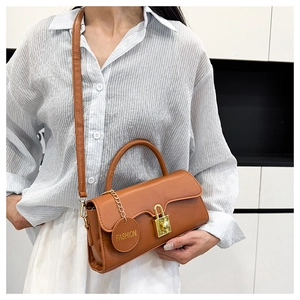 Detail of a brown leather crossbody bag with a gold lock and a FASHION tag decoration