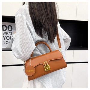 Détail d'un sac à main en cuir marron avec fermoir doré et pendentif mode rond
