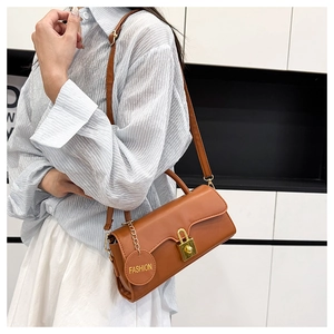 Detail of caramel faux leather handbag with golden square lock and fashion charm