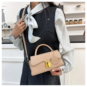 Detail of beige leather bag featuring a gold metal lock and hanging fashion tag