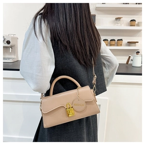 Détail du sac à bandoulière en similicuir beige avec fermoir doré et badge 'FASHION'