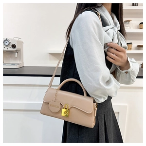 Detail of a beige leather crossbody bag featuring a gold padlock and FASHION charm