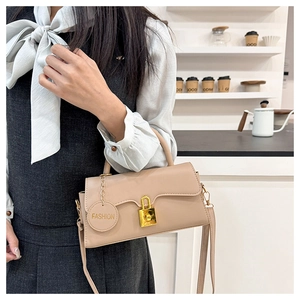 Detail view of beige square shoulder bag with gold twist lock and elegant leather strap