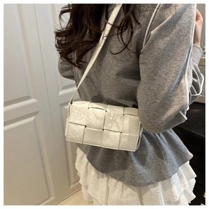 Close-up of white woven crossbody bag with snake-skin embossed texture and thin strap