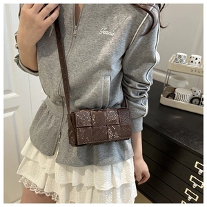 Detailed view of dark brown woven textured square crossbody bag worn by a model