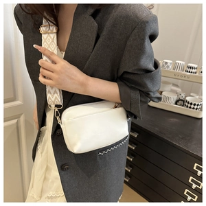 White crossbody bag with wide geometric jacquard strap worn by a model in casual setting