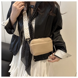 Detail of beige crossbody bag with geometric pattern woven wide shoulder strap on model