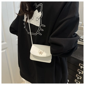 Detail of a creamy white mini crossbody bag featuring a golden butterfly metal buckle