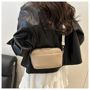 Beige leather crossbody bag featuring geometric patterned wide strap and gold hardware
