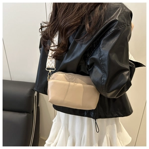 Detail of apricot crossbody bag with wide black and white geometric patterned strap