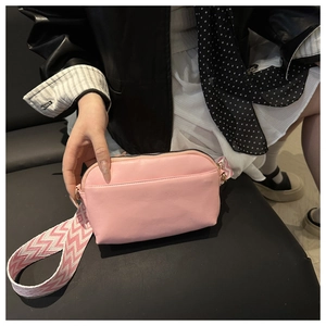 Detail of pink half-moon crossbody bag featuring wide woven geometric pattern strap