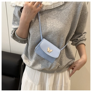 Mini light blue crossbody bag with golden butterfly buckle worn by a model