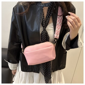 Sac bandoulière rose avec large sangle à motifs, porté par un mannequin en veste cuir