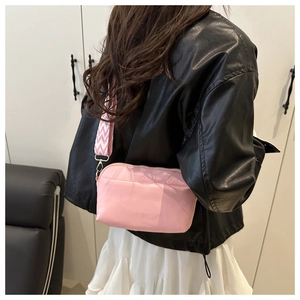 Pink crossbody bag with a wavy patterned fabric strap shown on a model in a black jacket