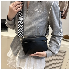 Detail of black crossbody square bag featuring a wide geometric pattern fabric strap