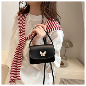 Mini black leather bag featuring a white butterfly buckle worn with a casual outfit