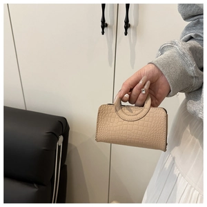 Close-up of beige crocodile pattern texture on a structured mini PU handbag
