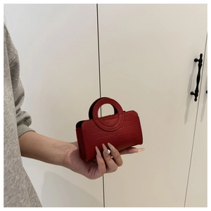 Detail of red croc-embossed micro bag with unique circular handle held by a model