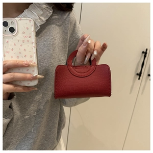 Close-up of red mini handbag showing crocodile texture and circular handle detail