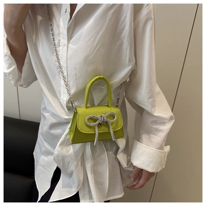 Détail du mini sac vert citron avec nœud en strass et chaîne argentée