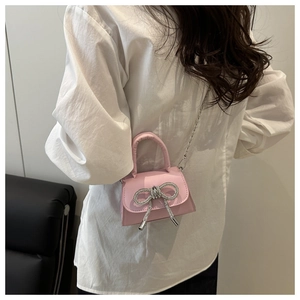 Detail of pink mini bag featuring silver rhinestone bow and delicate chain strap