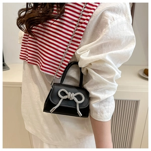 Detailopname van mini crossbodytas met kristallen strik en zilveren ketting op model