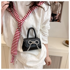 Détail du sac bandoulière noir avec nœud en strass étincelant et bandoulière chaîne
