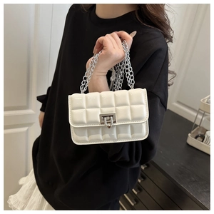 Detailed view of white quilted crossbody bag with silver lock and glossy finish