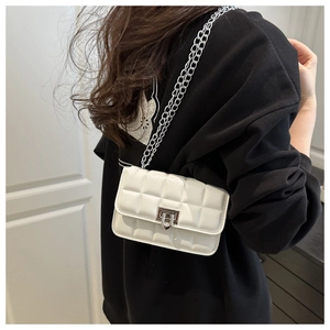Detailed view of silver twist lock and quilted pattern on white patent leather bag