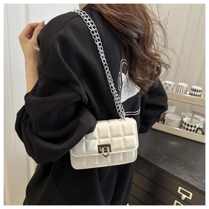Detail of white quilted patent leather crossbody bag with silver chain and metal lock