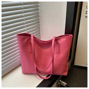 Detail of bright pink tote bag featuring crocodile pattern texture and long handles