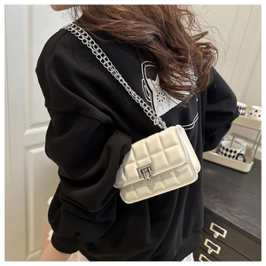Close-up of a white patent leather quilted crossbody bag with silver chain and metal lock