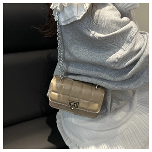 Detail of light khaki quilted crossbody bag with silver chain strap and metallic lock