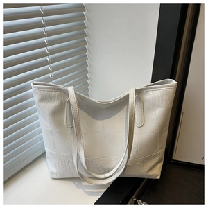 Detailed view of white crocodile pattern patchwork tote bag on a sunlit window sill