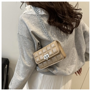 Detail of beige patent leather crossbody bag with square quilted texture and silver chain