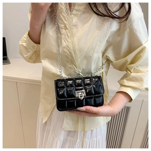 Detail of a black quilted chain bag on a model showing sizing and shiny leather texture