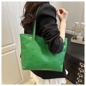 Detailed view of a bright green PU leather tote bag with crocodile texture on model