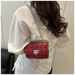 Model view of red quilted patent leather mini bag with silver chain strap and metal lock
