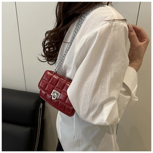 Macro detail of red quilted patent leather mini bag with silver chain and metal lock