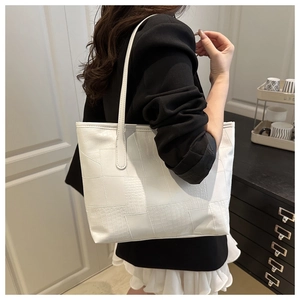 Chic white tote bag with crocodile texture shown on shoulder with a black blazer