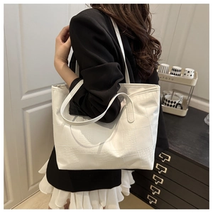 Detail view of white crocodile pattern tote bag with rich texture and long strap shoulder style