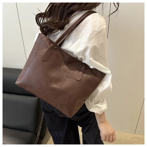 Detail view of large brown tote bag with premium animal skin texture stitching and straps